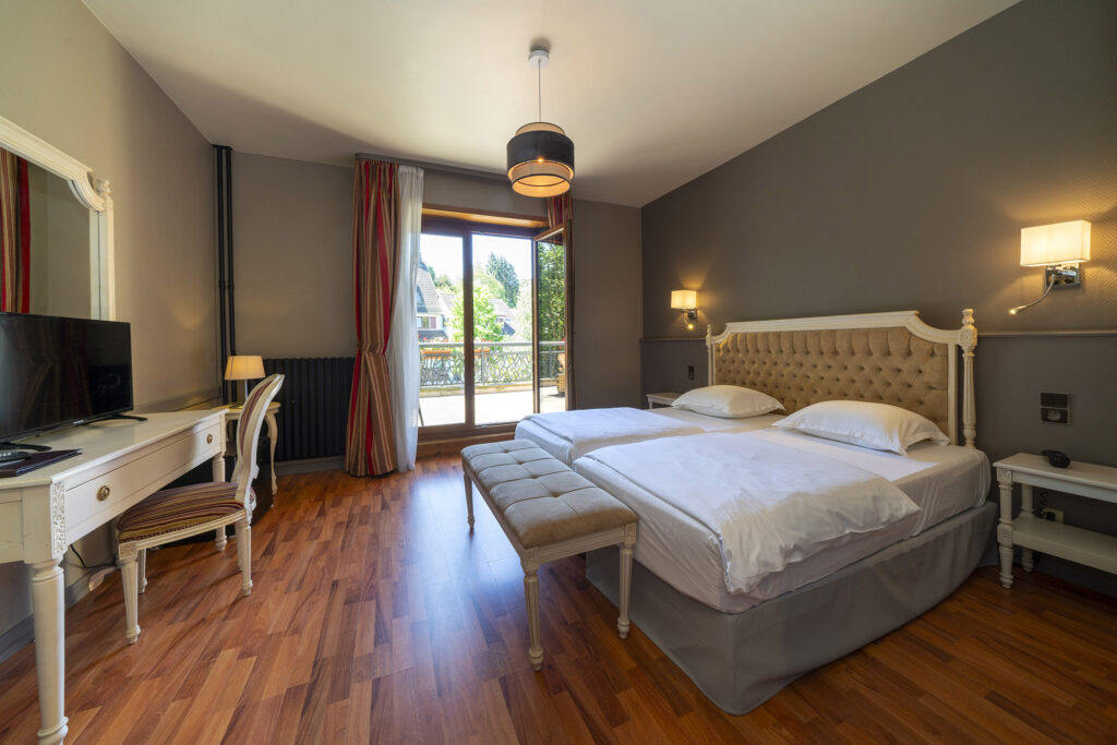 Tweepersoonskamer met balkon, bureau en houten vloer in H&ocirc;tel du Parc